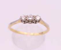 An 18 ct gold three stone diamond ring. Ring size R/S. 2.6 grammes total weight.