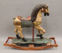A painted wooden rocking horse. Approximately 88 cm long.