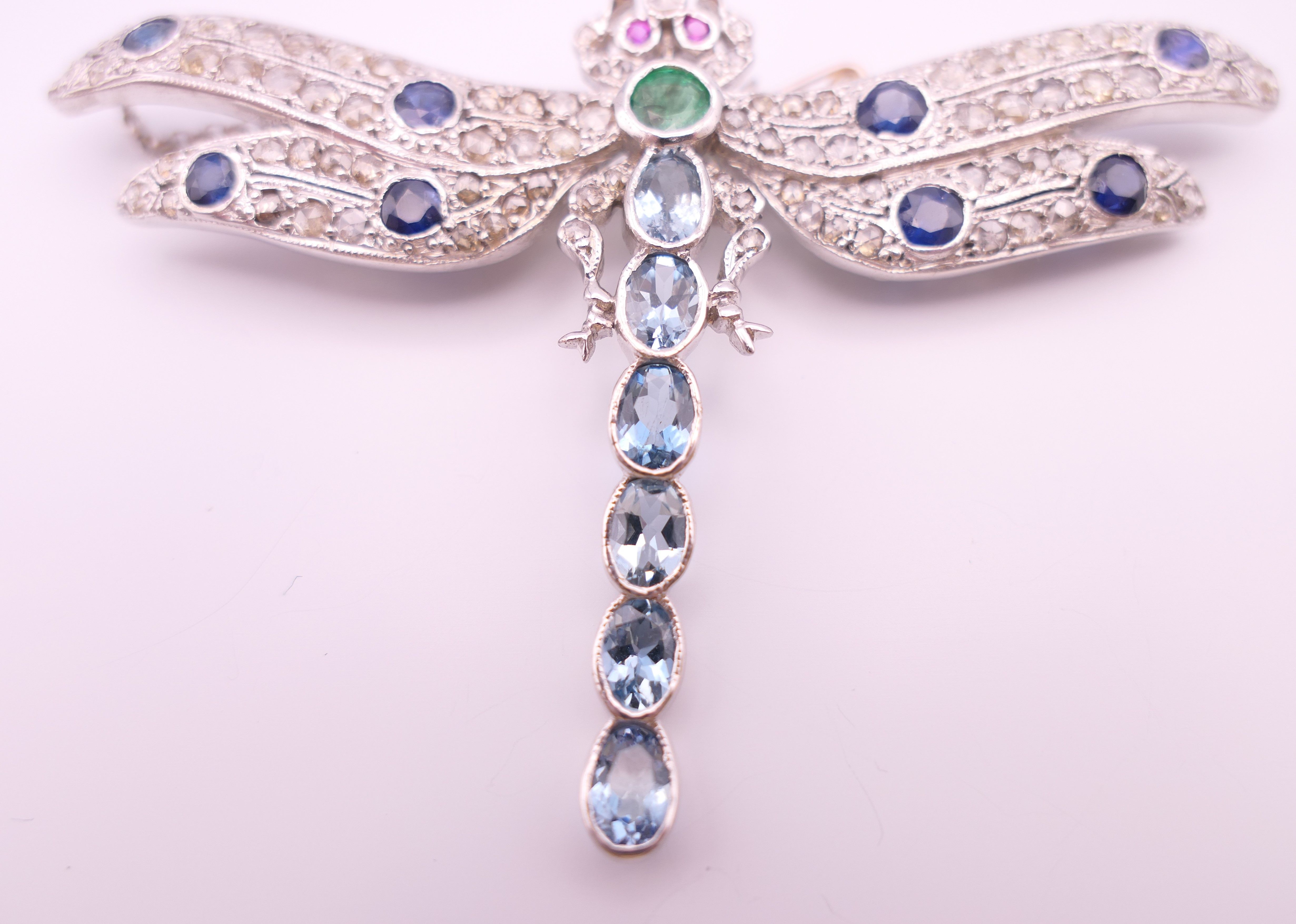 An unmarked 18 ct white gold dragonfly form diamond, sapphire, ruby, emerald and aquamarine brooch. - Image 4 of 11