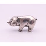 A small white metal model of a pig. 2.5 cm long.