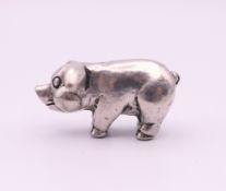 A small white metal model of a pig. 2.5 cm long.