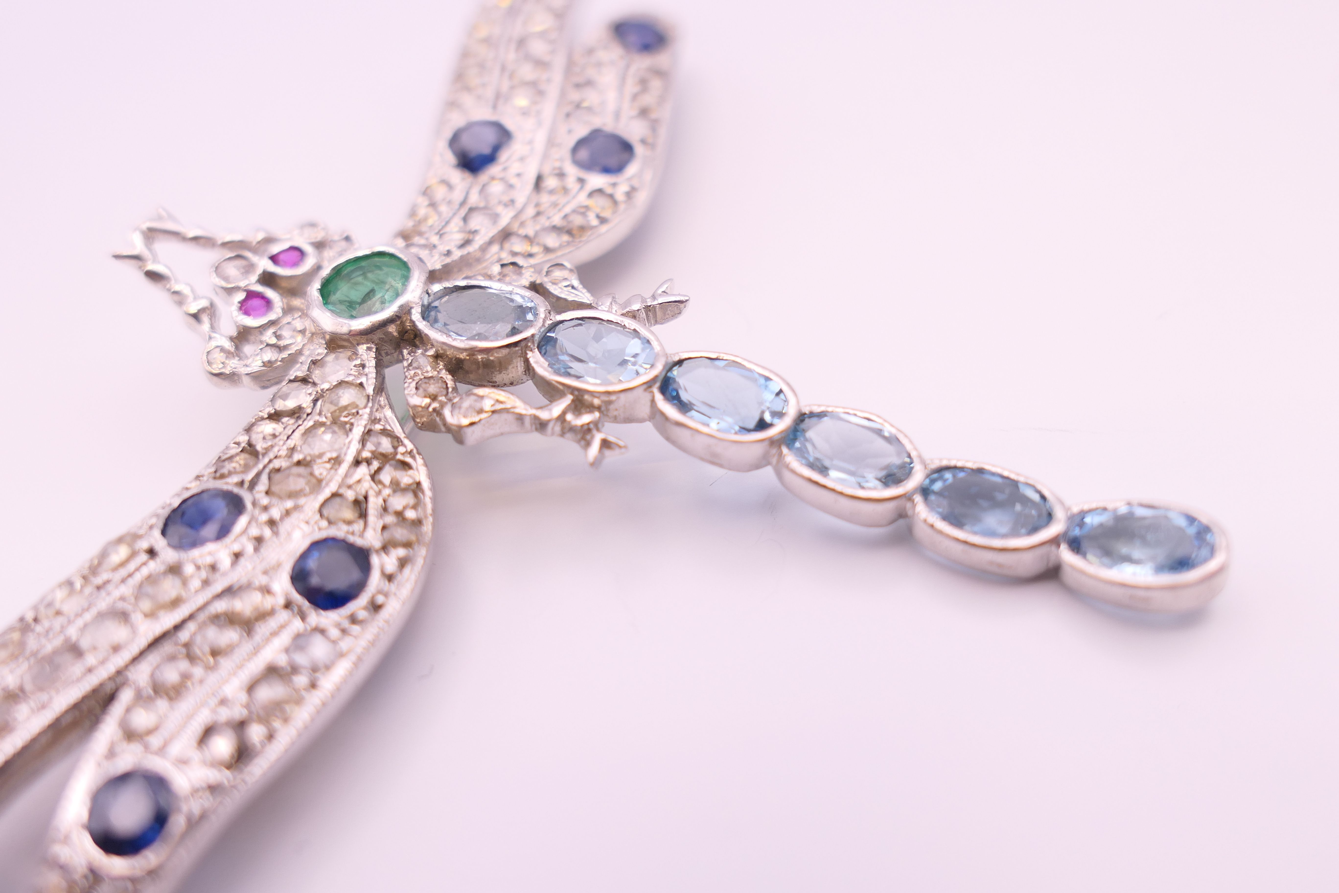 An unmarked 18 ct white gold dragonfly form diamond, sapphire, ruby, emerald and aquamarine brooch. - Image 10 of 11