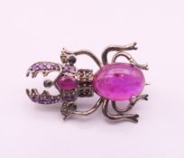 A diamond and ruby beetle form brooch. 2.75 cm long.