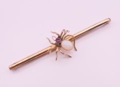 A 9 ct gold opal and ruby spider form brooch. 7.75 cm long. 6.1 grammes total weight.