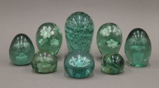 A collection of eight green glass dump weights. The largest 15 cm high.