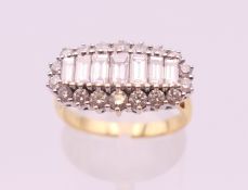An 18 ct gold ring with row of baguette diamonds surrounded with brilliant cut diamonds.