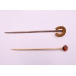 A 15 ct gold horseshoe stick pin and another. Horseshoe pin 5.5 cm long. 1.5 grammes total weight.