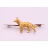 A 9 ct gold bar brooch, set with an unmarked 15 ct gold Alsatian. 5 cm long, dog 2.25 cm long. 7.