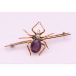A 9 ct gold opal and amethyst spider form brooch. 6 cm long. 5.9 grammes total weight.