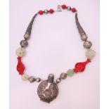 A cinnabar, pierced jade and white metal necklace. Necklace 64 cm long, snuff bottle 8.5 cm high.