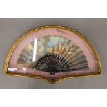 A Spanish hand coloured fan in a bespoke gilt display case. The case 62 cm wide.