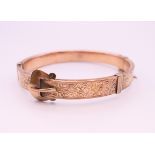 A 9 ct gold buckle form bangle bracelet. 5.75 cm internal diameter. 12.4 grammes total weight.