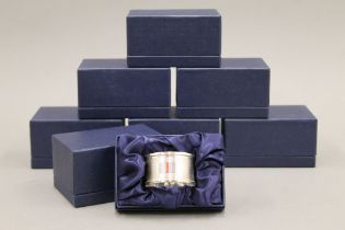 A set of eight silver napkin rings, in boxes. Approximately 128 grammes.