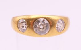 An 18 ct gold three stone diamond ring. The central stone spreading to approximately .75 carat.
