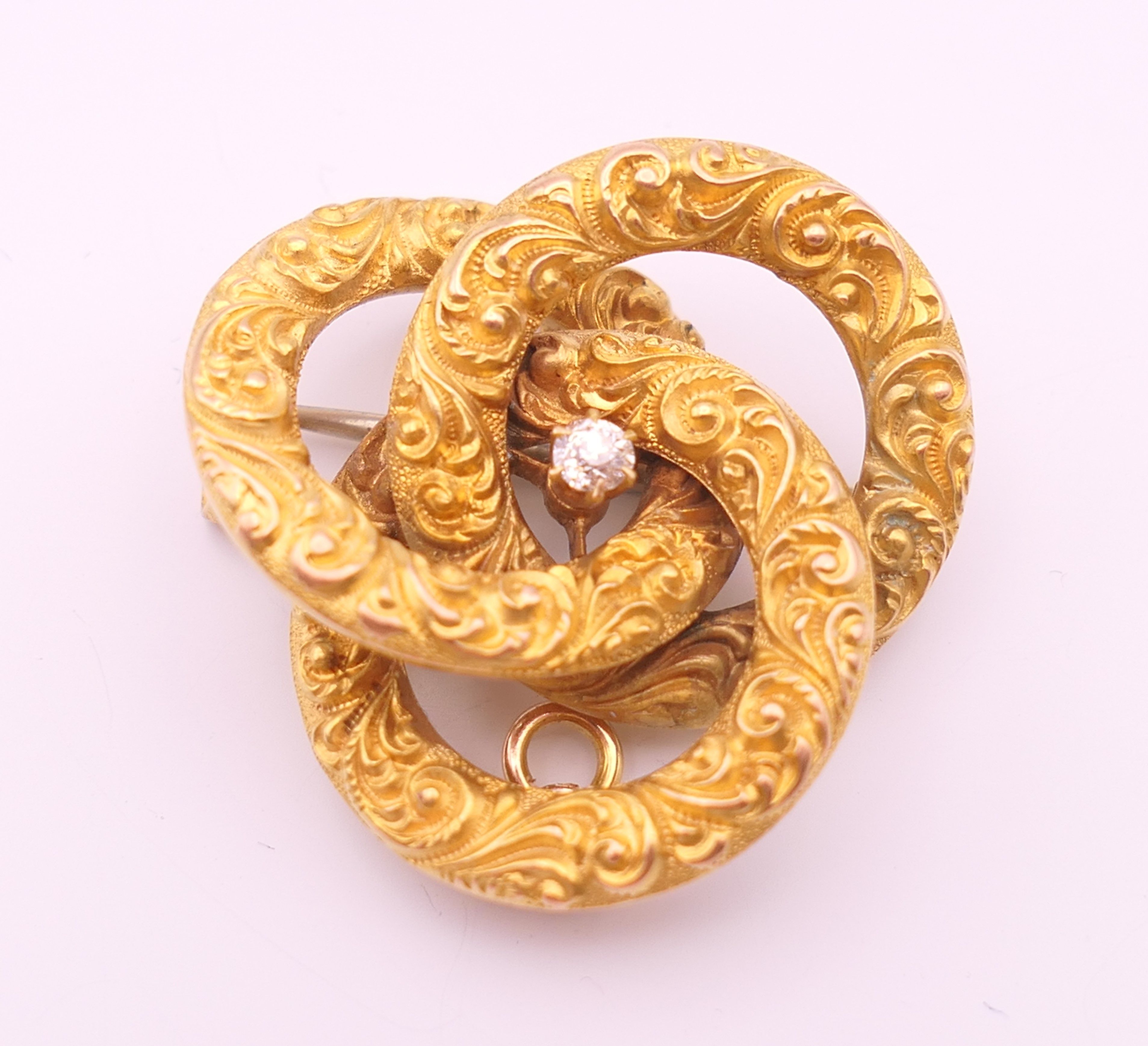 An unmarked 15 ct gold and diamond brooch/pendant formed as three interlocking circles.