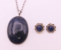 A silver and lapis pendant on chain and a pair of earrings.