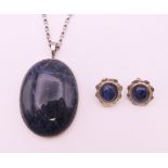 A silver and lapis pendant on chain and a pair of earrings.