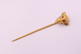 A 9 ct gold and ruby bulls head form stick pin. 5.75 cm high. 1.7 grammes total weight.