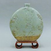 A celadon moon vase on a wooden stand. 29 cm high.