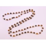 A string of tigerseye and pearl beads. 120 cm long.