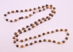 A string of tigerseye and pearl beads. 120 cm long.