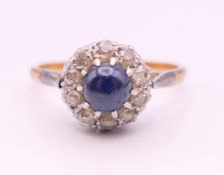 An 18 ct gold and platinum cabochon sapphire and diamond cluster ring. Ring size Q.