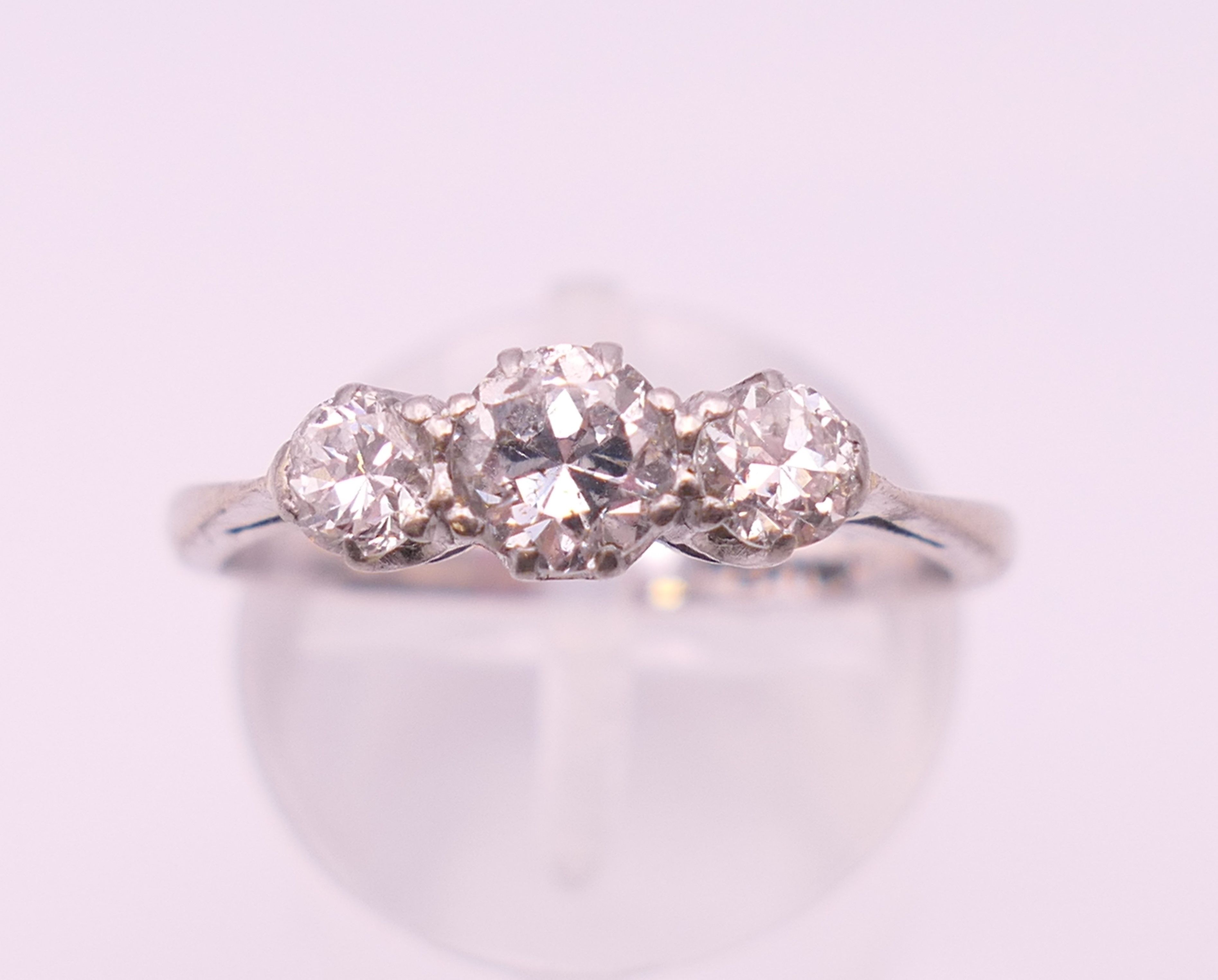 A platinum three stone diamond ring. Ring size P.