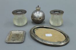 A pair of silver topped match strikers, a small silver dish, a table lighter and a silver frame.