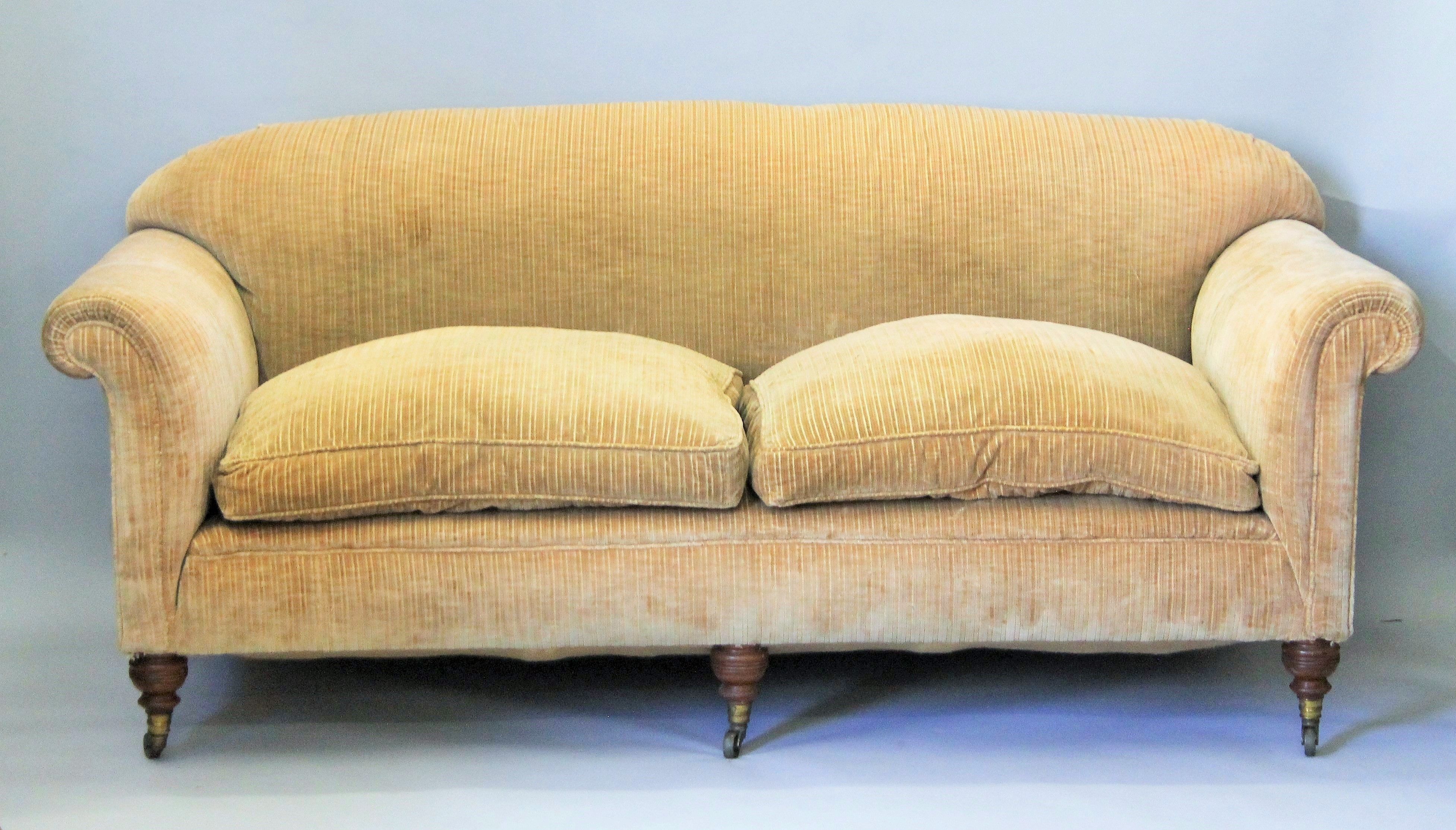 A large Victorian upholstered settee by Howard and Sons, with three turned front legs,