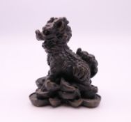 A bronze model of a dog-of-fo on pile of money. 5 cm high.
