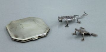 A silver compact and two white metal lizards. The former 6.5 cm wide.