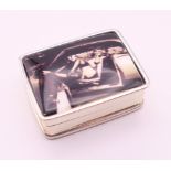 A silver pill box depicting a semi clad woman in a car. 3.25 x 2.5 cm.