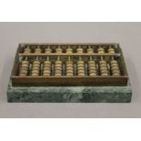 A small brass and green marble abacus. 8.75 cm long.