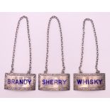 A set of three silver enamel wine labels for Whisky, Brandy and Sherry. Each 5 cm x 2.5 cm.