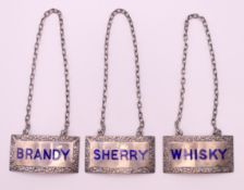 A set of three silver enamel wine labels for Whisky, Brandy and Sherry. Each 5 cm x 2.5 cm.