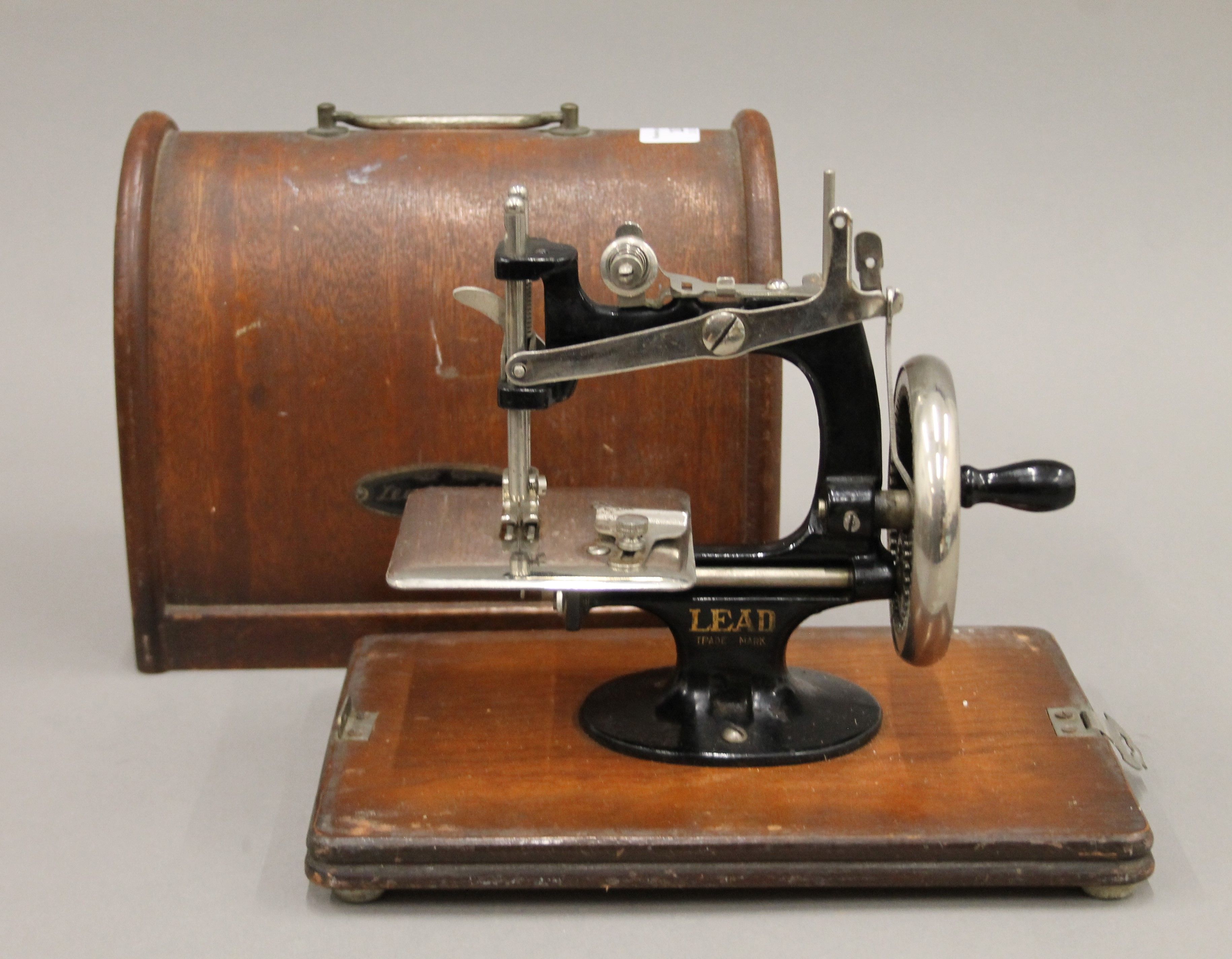 A miniature 'LEAD' sewing machine and case. The case 23 cm long.