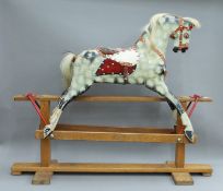 An early 20th century dapple grey painted wooden rocking horse. 105 cm long x 87 cm high.