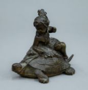 A bronze model of a child riding a tortoise. 8 cm high.