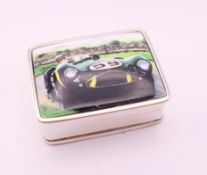A silver pill box depicting a racing car. 3.25 x 2.5 cm.
