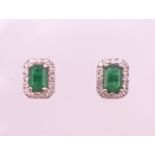 A pair of 18 ct white gold rectangular emerald and diamond stud earrings. 9 mm high.