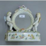 A cherub form porcelain mirror. 27.5 cm high.