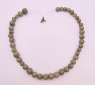 A carved jade necklace. Approximately 48 cm long.