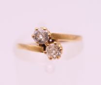 An 18 ct gold diamond two stone cross over ring. Total diamond weight approximately 0.25 carat.