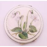 A silver and enamel compact of circular form, painted with a flowering plant, Birmingham 1955. 7.