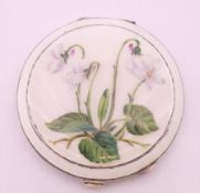 A silver and enamel compact of circular form, painted with a flowering plant, Birmingham 1955. 7.