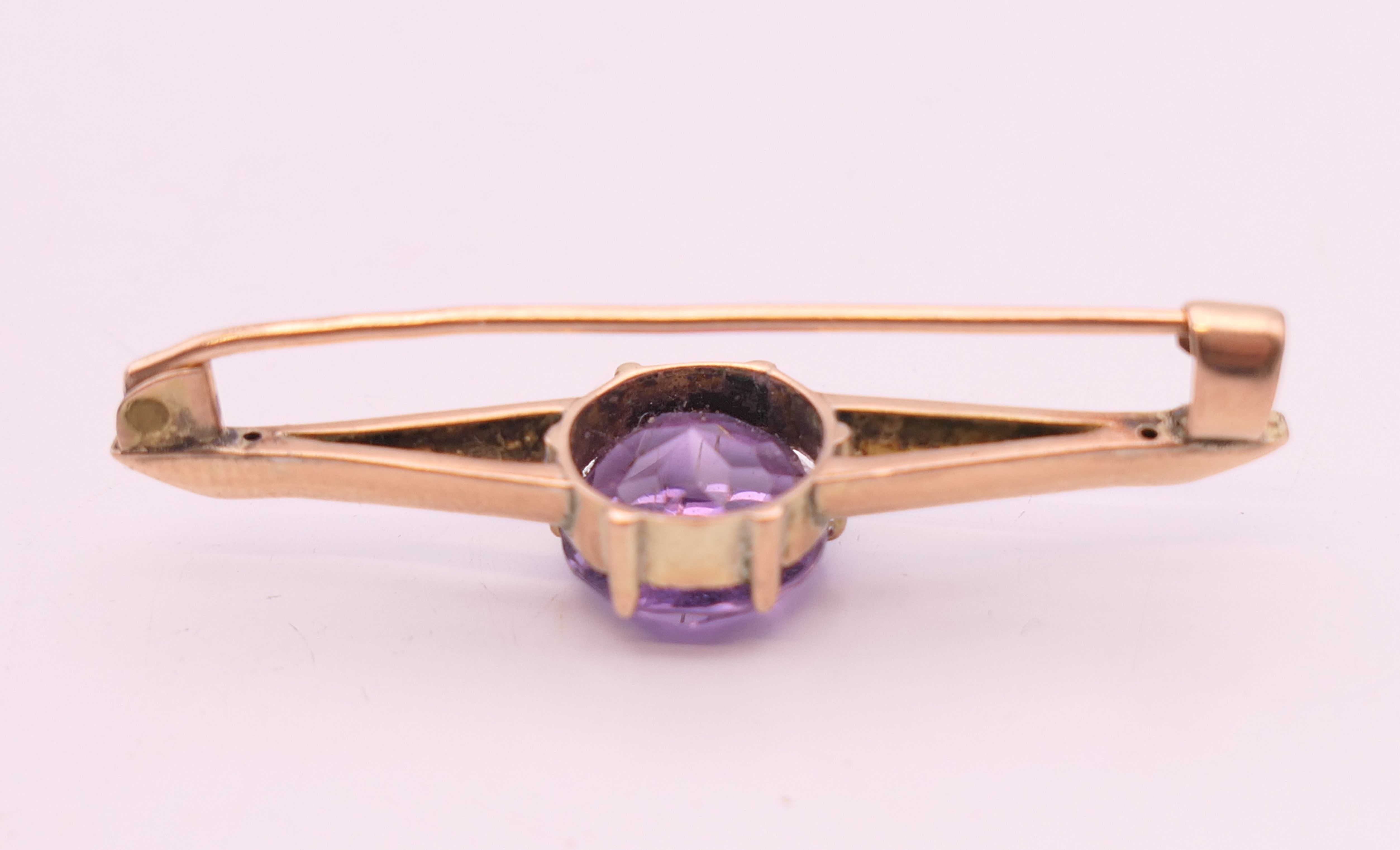 An unmarked 9 ct gold and amethyst bar brooch. 4 cm wide. 2.9 grammes total weight. - Image 3 of 3