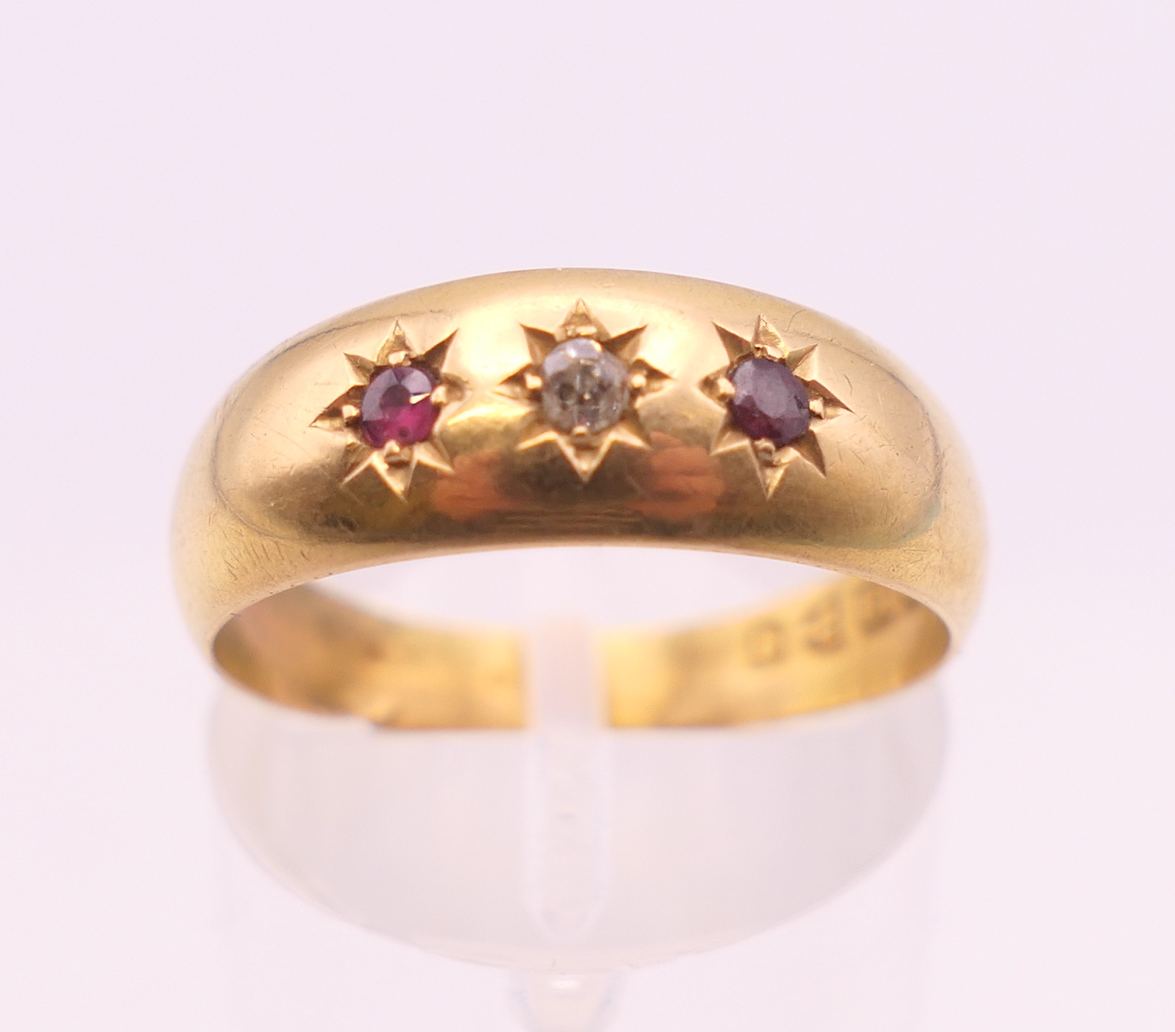 An 18 ct gold ruby and diamond three stone gypsy set ring. Ring size O. 2.3 grammes total weight.
