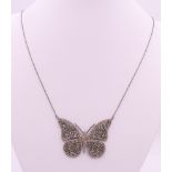 A diamond and emerald butterfly pendant necklace. 5 cm wide.