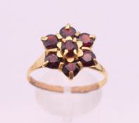 A garnet set gold flowerhead ring. Ring size V/W. 3.6 grammes total weight.