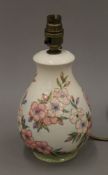A William Moorcroft pottery lamp base decorated with pink flowers and buds on a green and cream